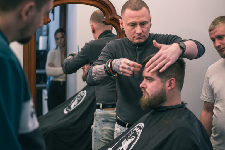 Fryzjer Gorzów Wielkopolski precyzyjnie stylizujący męską fryzurę w profesjonalnym barbershopie.